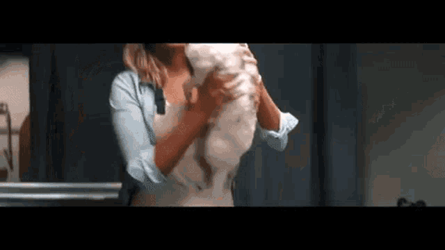 a woman is holding a white dog in her arms in a kitchen .