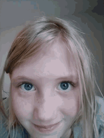 a young girl with blonde hair and blue eyes is smiling