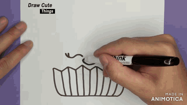 a person is drawing a cupcake on a piece of paper