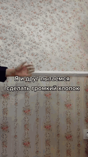 a person 's hand is reaching out towards a wall with a floral wallpaper