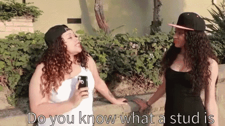 two women are standing next to each other and one is holding a cell phone and the other is holding a stud in her hand .
