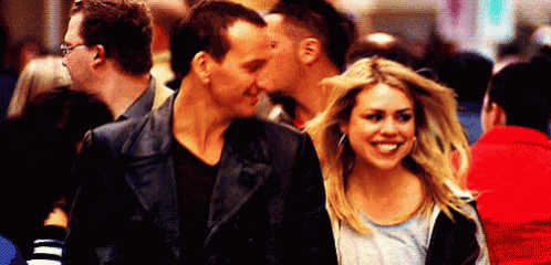 a man and a woman are walking down a crowded street and smiling .