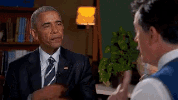 a man in a suit and tie is talking to another man in a room