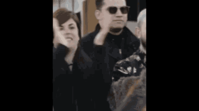 a woman in a black coat is covering her mouth with her hands
