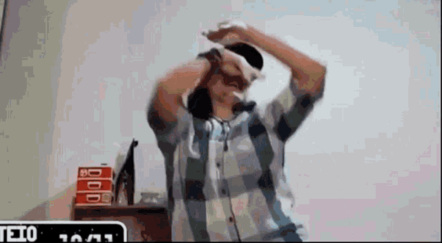 a man in a plaid shirt is wearing headphones and dancing .