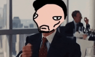 a man in a suit and tie is sitting at a table with a cartoon face on his head .