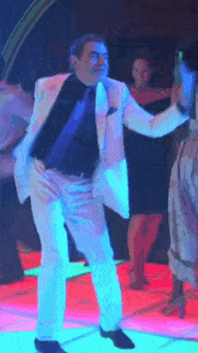 a man in a white suit is dancing on a neon dance floor