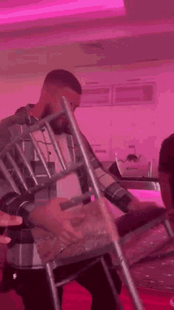a man is sitting on a chair in a room with pink lights .