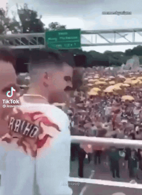 a man wearing a shirt that says rbhd is standing in front of a crowd of people .