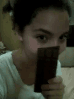 a girl is eating a piece of chocolate with her mouth open .