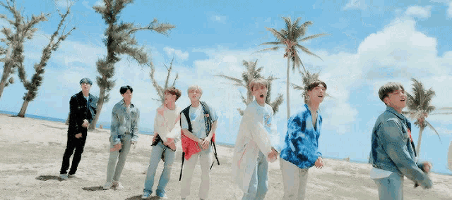 a group of young men are dancing on a beach with palm trees in the background