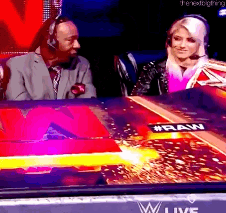 a man in a suit and tie is sitting next to a woman in a wrestling ring .