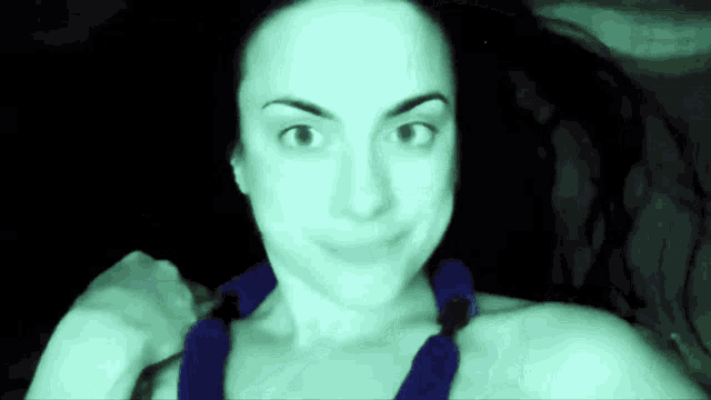 a woman with a blue tie around her neck is smiling in the dark