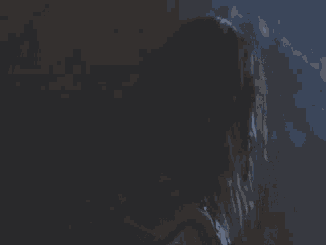 a man with long hair and a beard looks at the camera in the dark