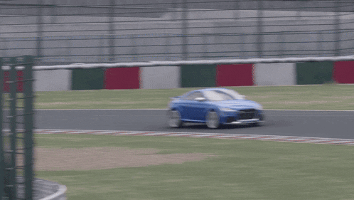 a blue sports car is driving on a race track