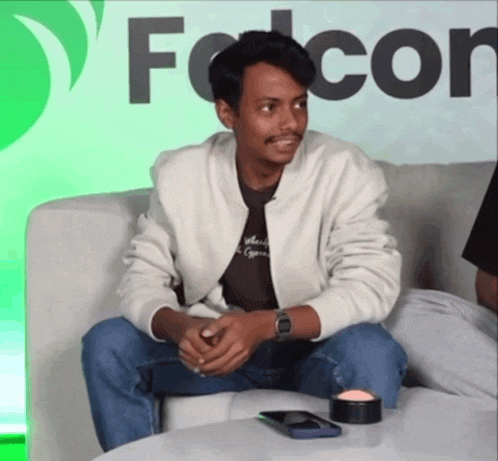 a man is sitting on a couch in front of a falcon sign