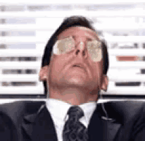 a man in a suit and tie is wearing sunglasses on his face .
