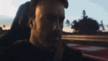 a man with a beard is sitting in the back seat of a car looking out the window .