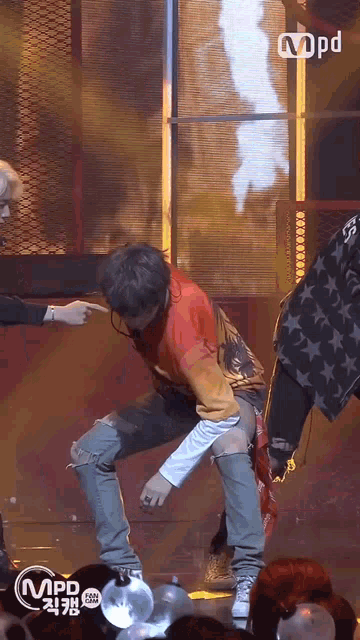 a man in a red shirt is dancing on a stage with a m pd logo in the corner