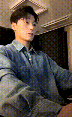 a young man in a denim shirt sits in a chair