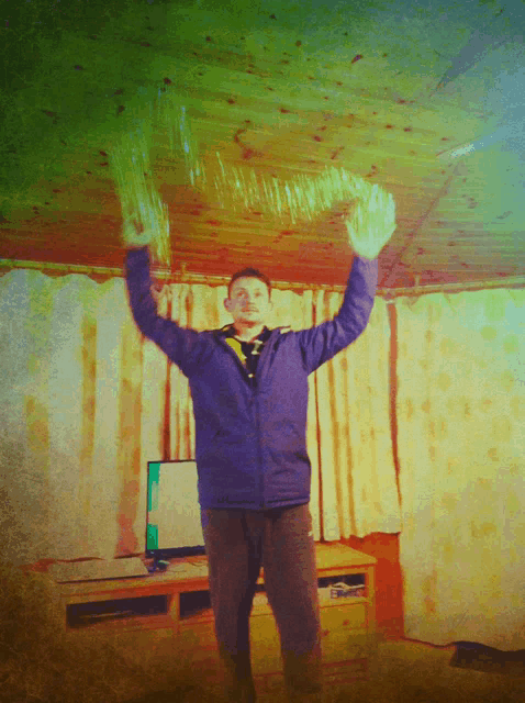 a man in a blue jacket is standing in front of a television with his arms in the air