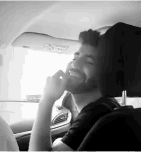 a man with a beard is sitting in a car with his eyes closed