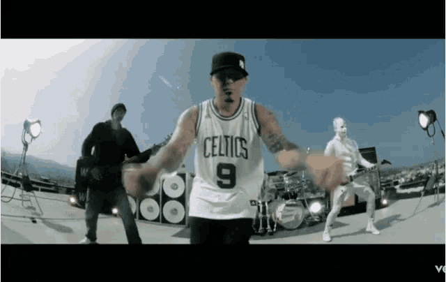 a man in a celtics jersey stands in front of a drum set