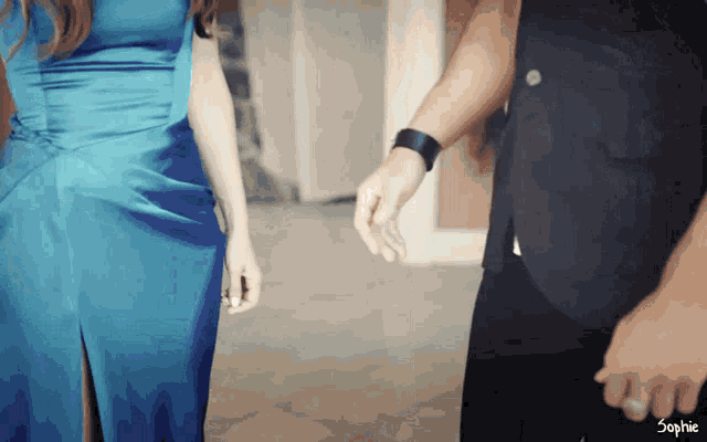 a woman in a blue dress is standing next to a man in a black suit with the word sophie on the bottom