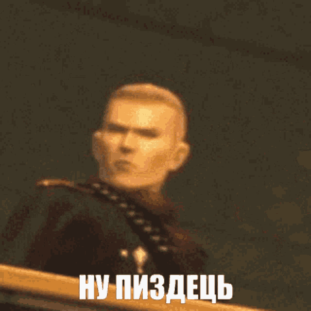 a man in a military uniform is standing in front of a sign that says " ну пиздаць "