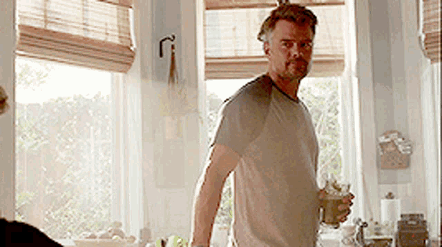 a man standing in front of a window holding a glass