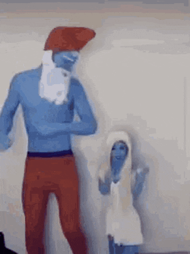 a man and a woman dressed as smurfs are dancing in front of a wall .