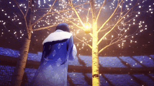 a woman in a blue coat is standing in front of a tree