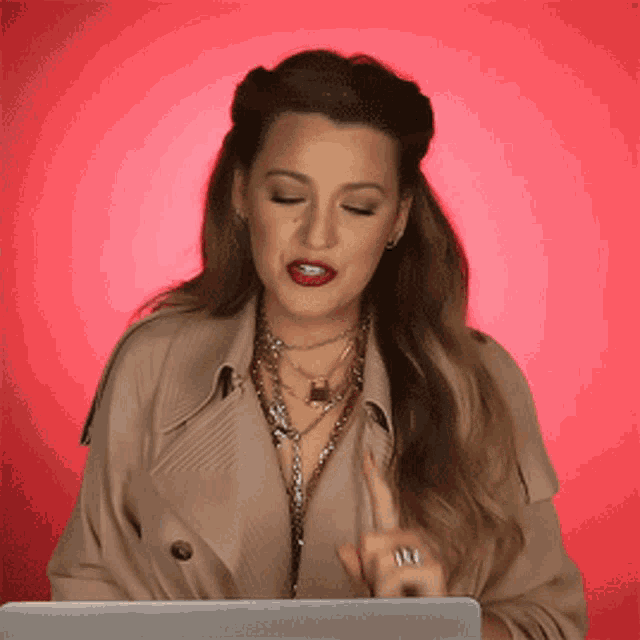 a woman in a trench coat is using a laptop computer