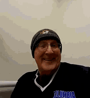 a man wearing a beanie and a columbia shirt smiles for the camera