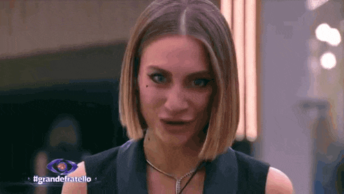 a woman is making a funny face in front of a sign that says " grandefratello "