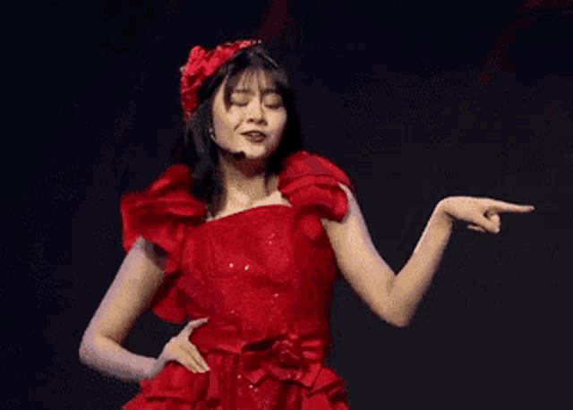 a woman in a red dress is dancing on a stage while wearing a microphone .