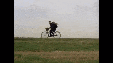a man is riding a bicycle in a field .