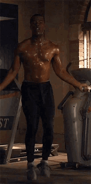 a shirtless man is jumping a jump rope in a gym next to a treadmill .