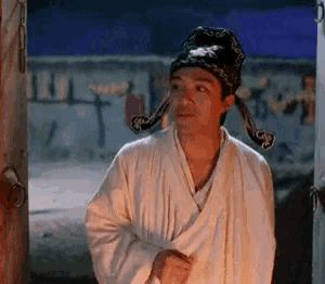 a man in a white robe and hat is standing in front of a door .
