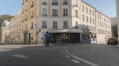 a man in a hat stands in front of a building that has a no entry sign on it