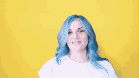 a woman with blue hair and a white shirt is waving her hand .
