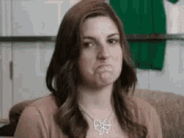 a woman wearing a bow necklace is making a funny face .