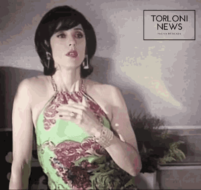 a woman in a green dress stands in front of a torloni news banner