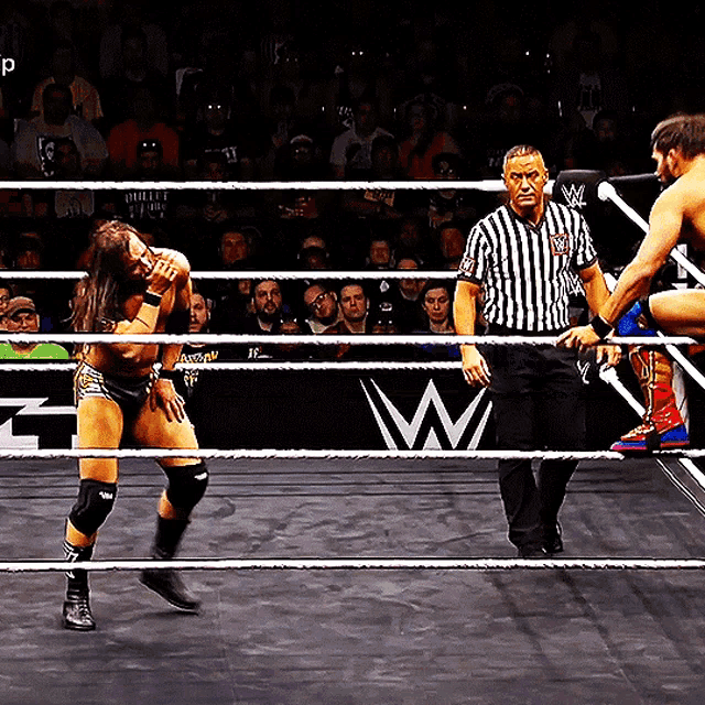a man in a wrestling ring with a referee and a sign that says w