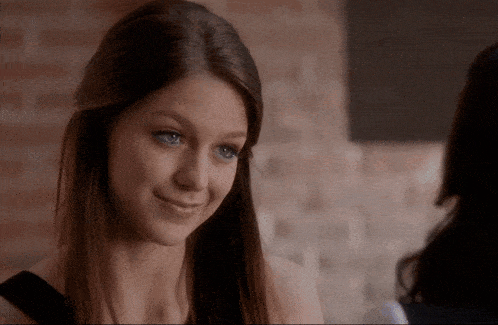 a woman with long hair and blue eyes smiles at another woman