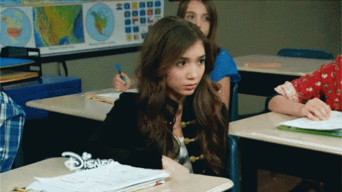 a girl sits at a desk in a classroom with a disney logo on her desk