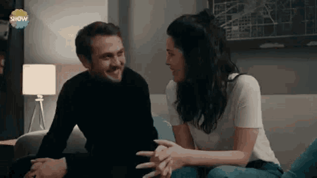 a man and a woman are sitting on a couch and holding hands .