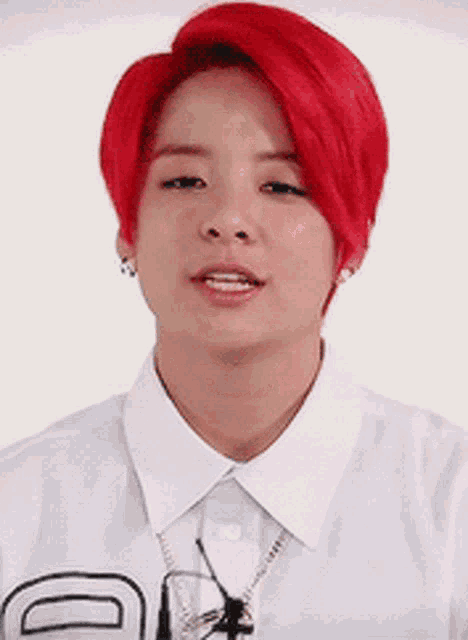 a man with red hair is wearing a white shirt and necklace