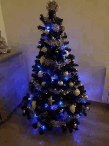 a black christmas tree with blue lights and silver ornaments