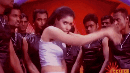 a woman is dancing in front of a group of men in black shirts .